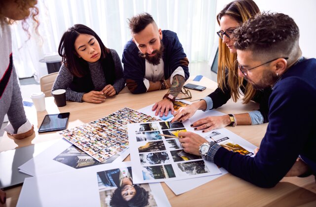 New Business office creative directors team at work together on tasks choosing the right image to use in a campaign.